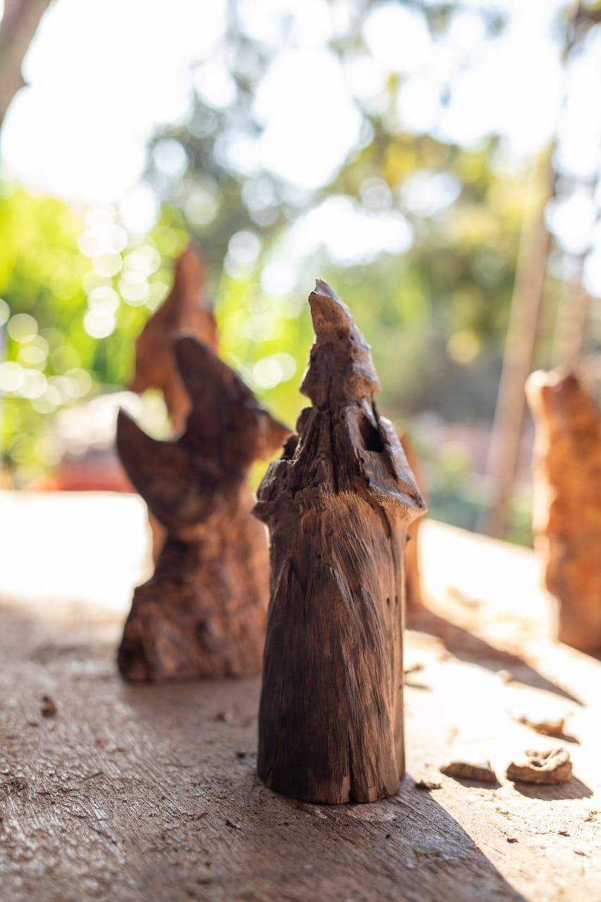 Escultura de madeira com forma orgânica sobre bancada do ateliê