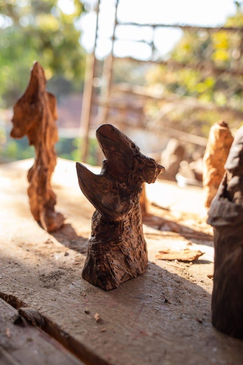 Pequena escultura de madeira sobre bancada no ateliê