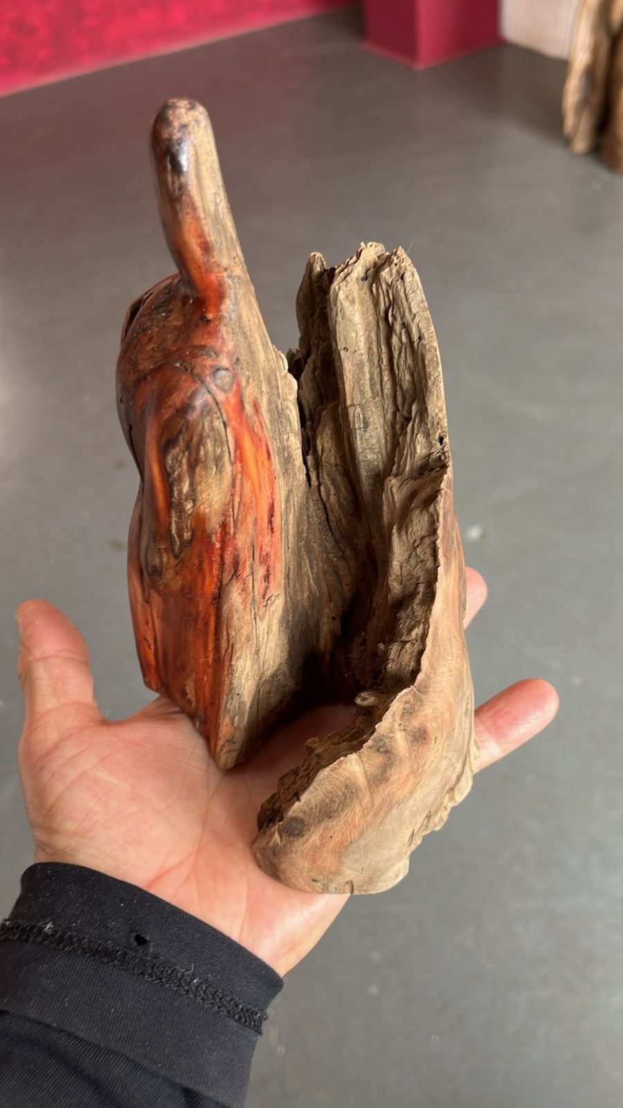 Pequena escultura de madeira sendo segurada pelas mãos da artista